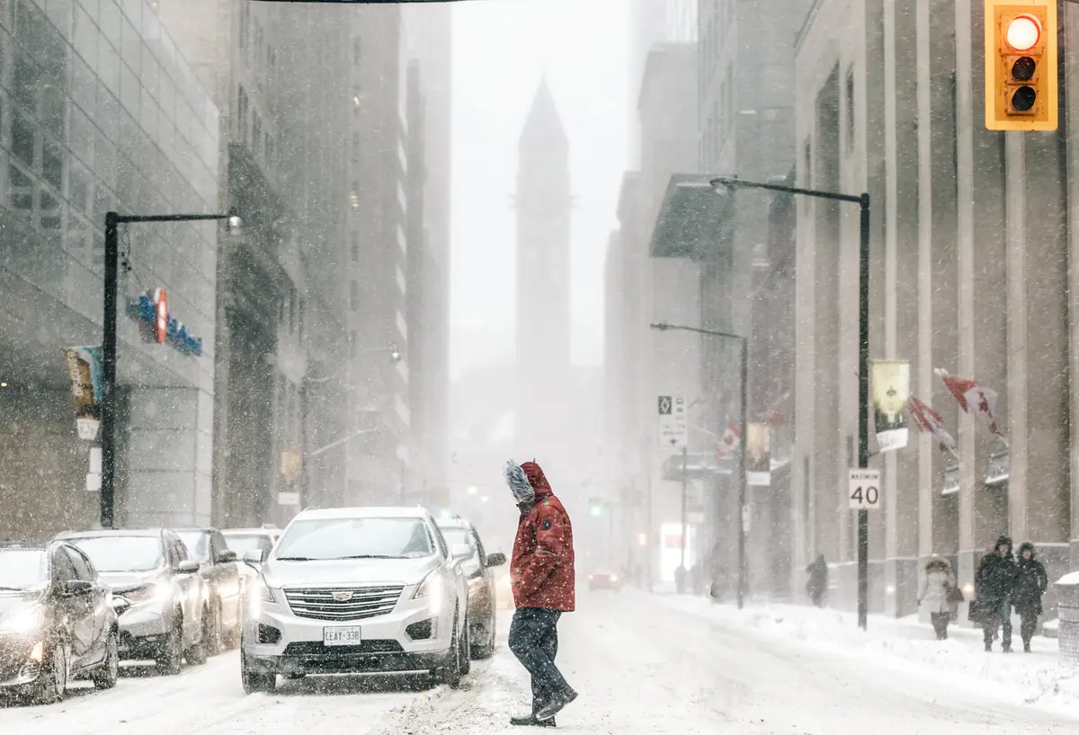 Homme en parka rouge traversant une rue en hiver