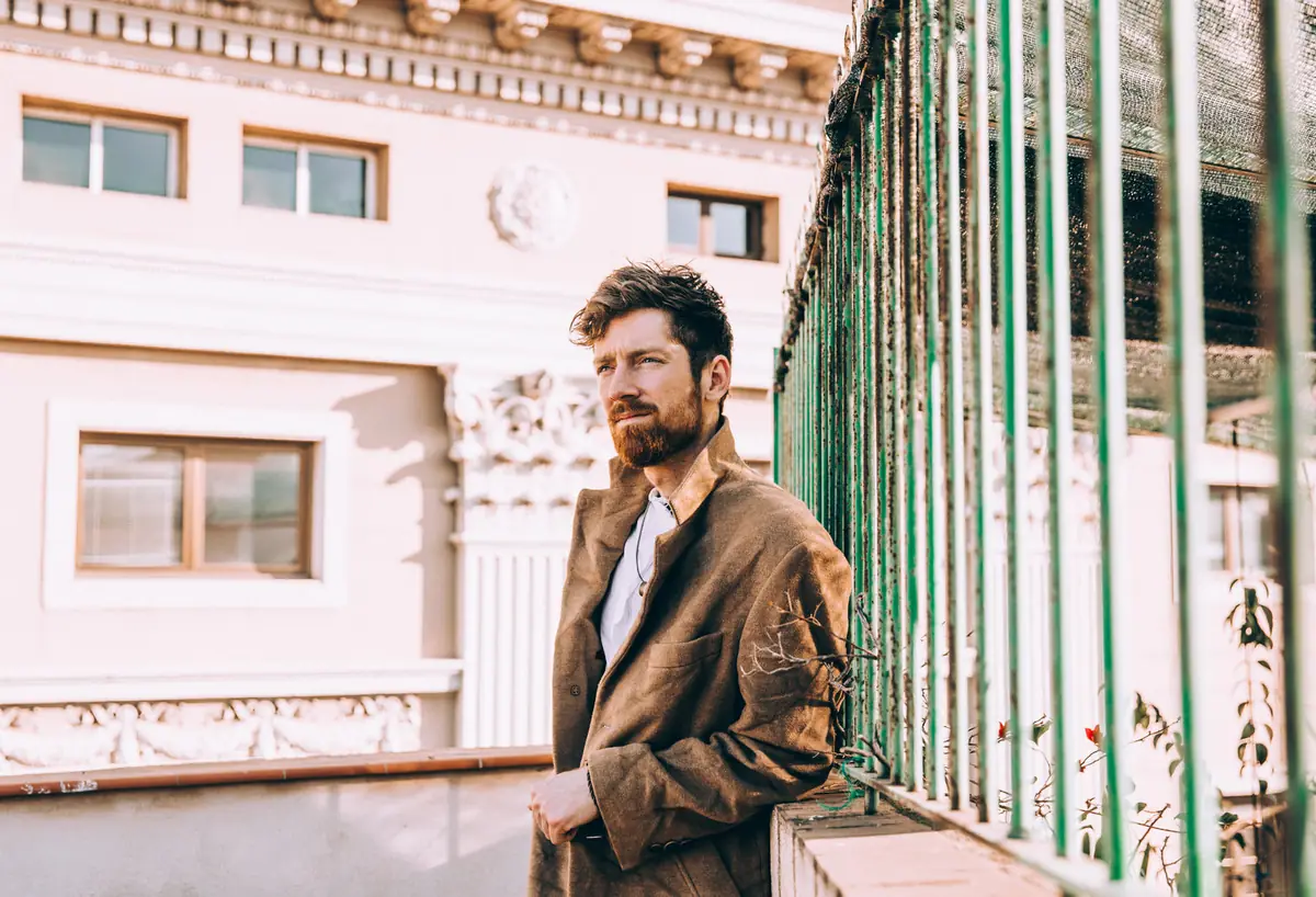 Man in a coat leaning against a railing
